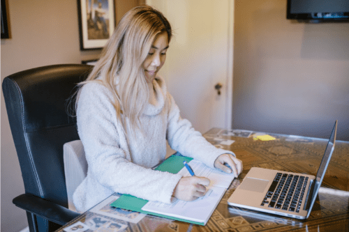 Girls sitting at dining table studying with a laptop and notebook