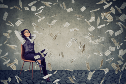 Businesswoman relaxing in a chair as money falls all around her