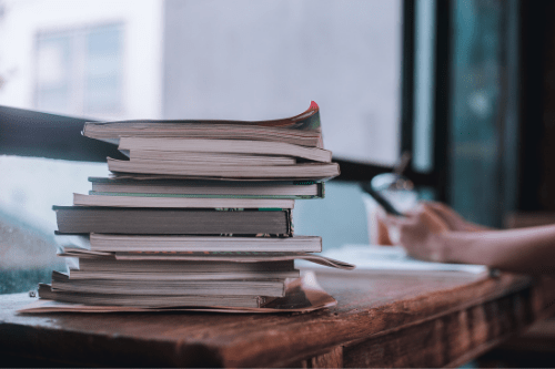 Books with student texting in the background