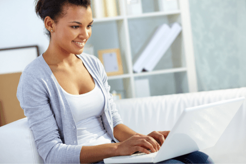 Female smiling at her computer screen and typing