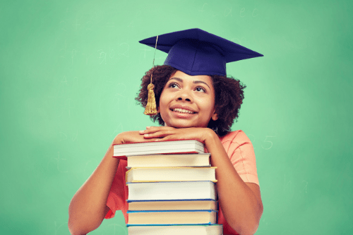 Black woman smiling for graduation photo with a stack of books