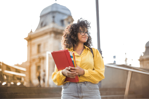 Happy student posing with school supplies on college campus